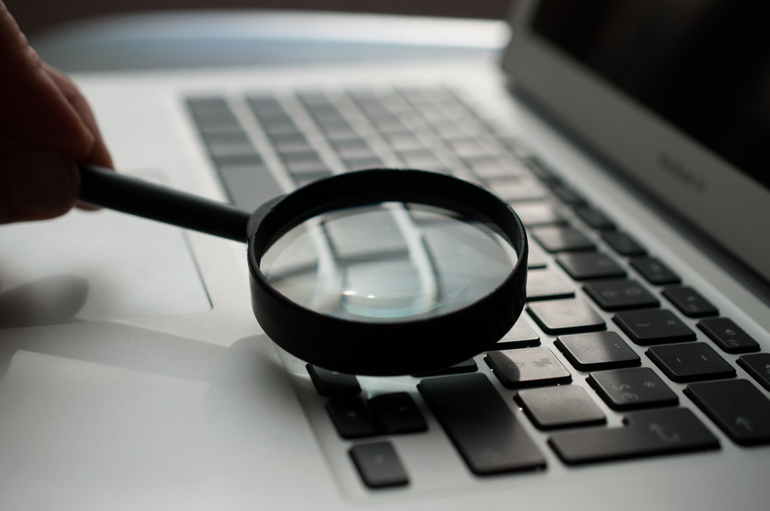 picture shows magnifying glass pointed at the keyboard of a laptop