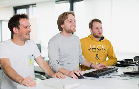 Drei Software-Enwickler von BSI im Gespräch am PC